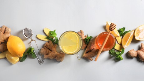 Photo of Glassaromatic ginger tea and ingredients on light grey background, flat lay