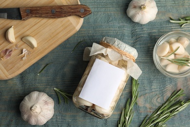 Flat lay composition with jar of pickled garlic on blue wooden table