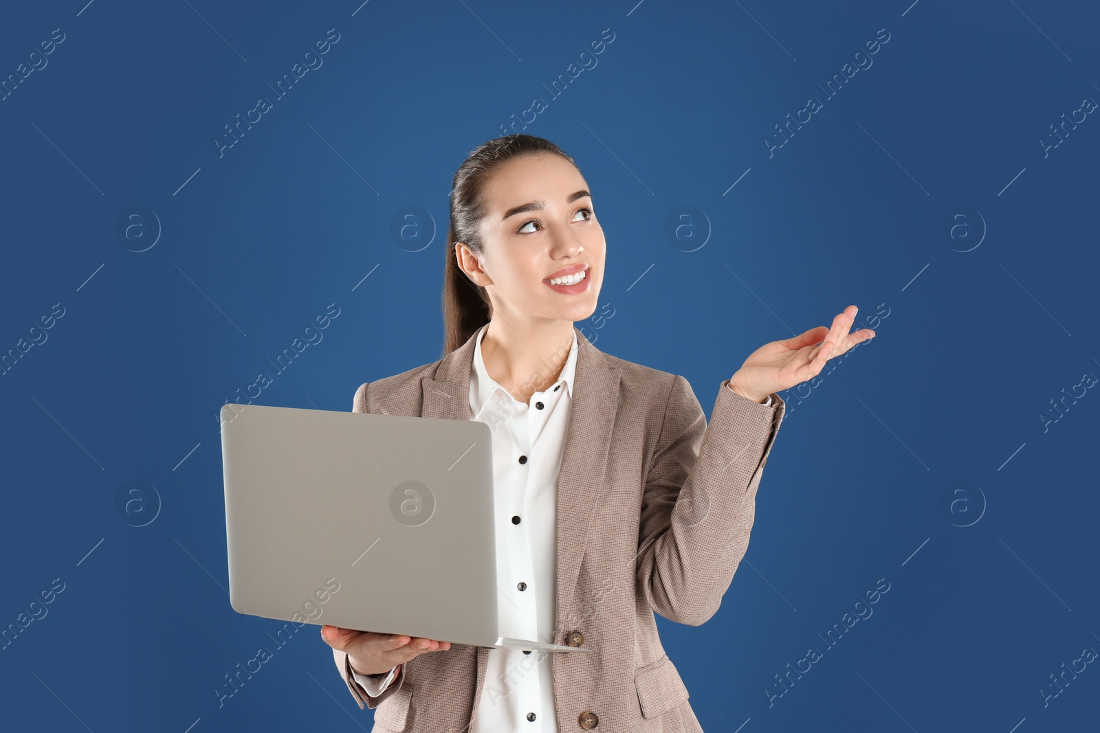 Photo of Portrait of young woman in office wear with laptop on color background