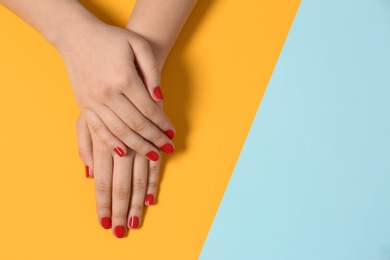 Photo of Woman showing red manicure on color background, top view with space for text. Nail polish trends