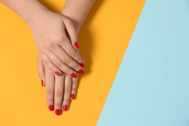 Woman showing red manicure on color background, top view with space for text. Nail polish trends