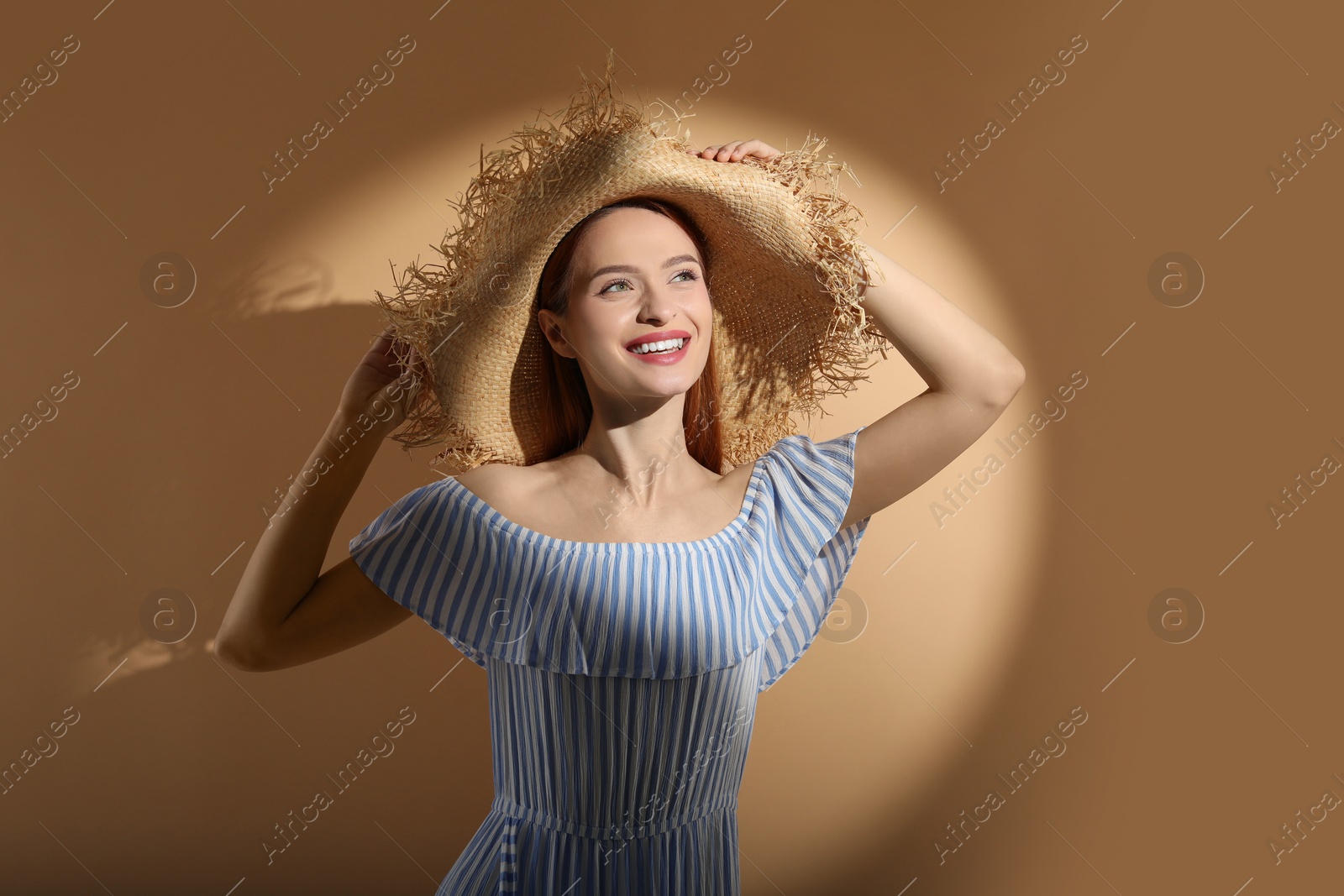 Photo of Beautiful young woman in sunlight on beige background