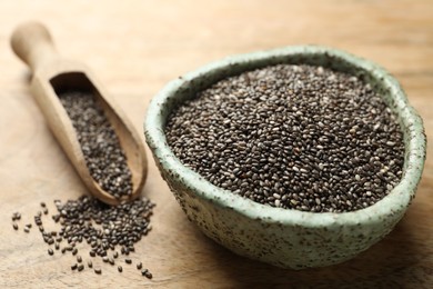 Photo of Bowl and scoop with chia seeds on wooden table, closeup