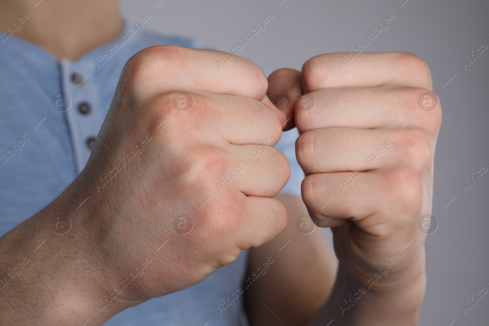 Photo of Man showing fists with space for tattoo on grey background, selective focus