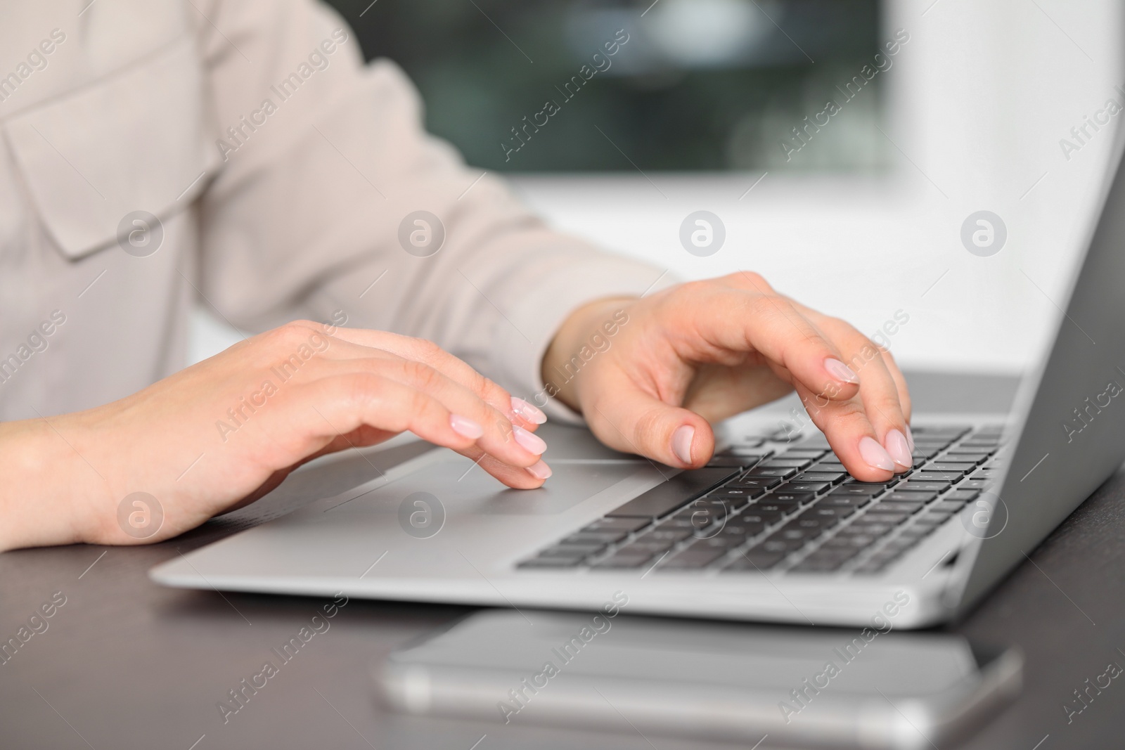 Photo of Woman working on laptop at table, closeup. Electronic document management