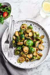 Photo of Delicious roasted brussels sprouts on white marble table, flat lay