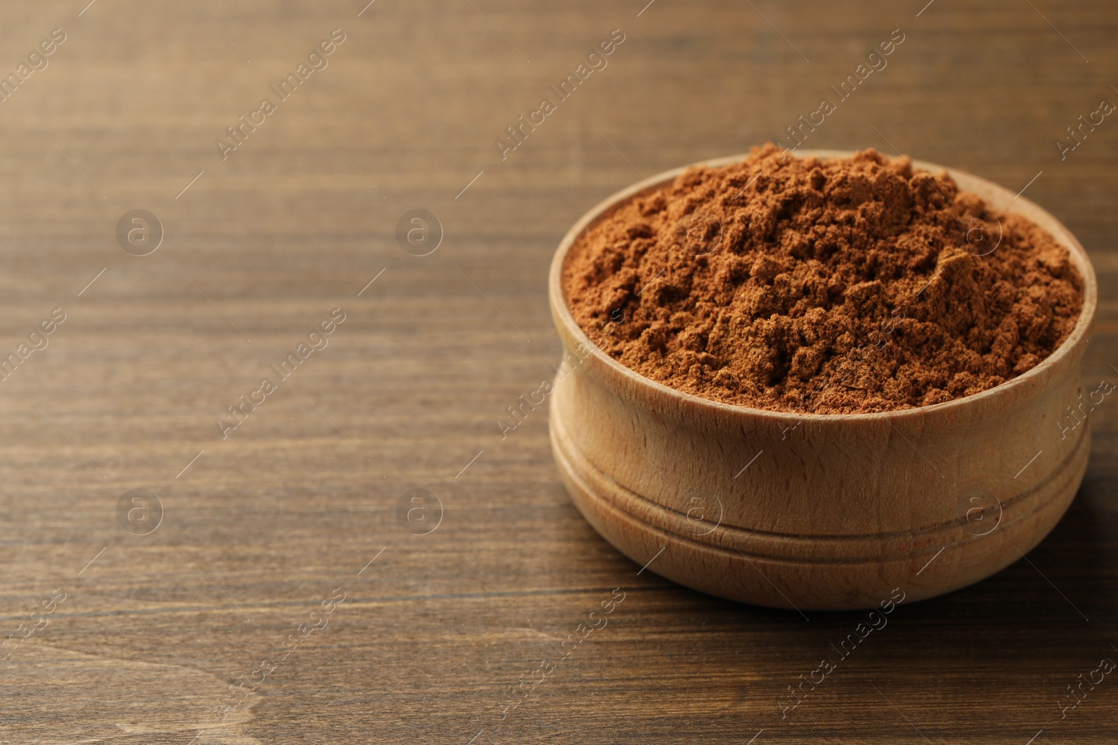 Photo of Aromatic cinnamon powder on wooden table, closeup. Space for text