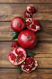 Flat lay composition with ripe pomegranates on wooden background