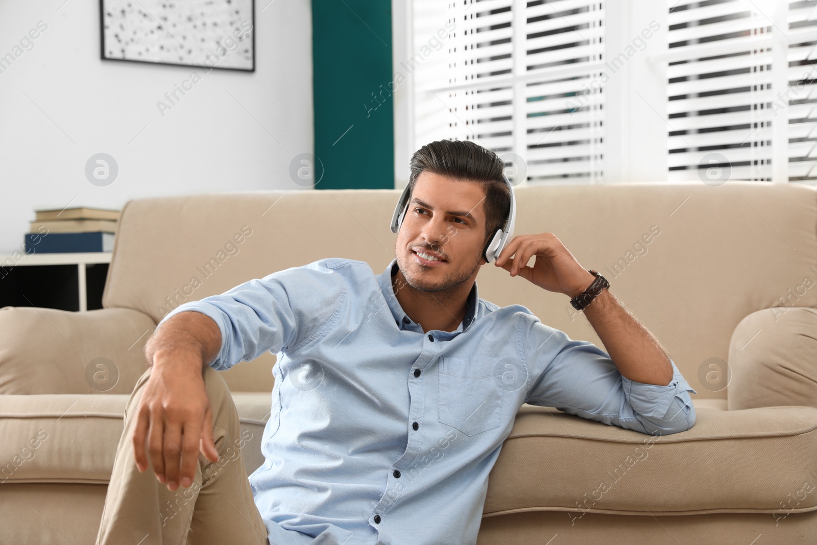 Photo of Man listening to audiobook near sofa at home