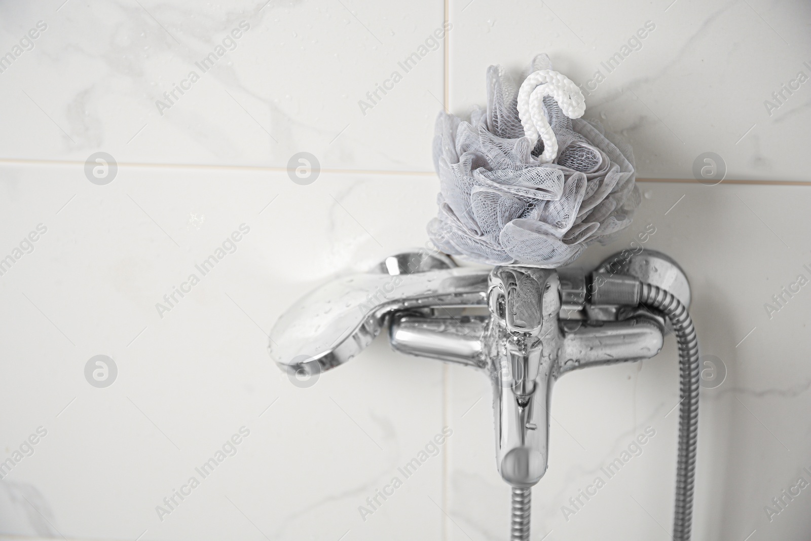 Photo of Grey shower puff on faucet in bathroom, space for text