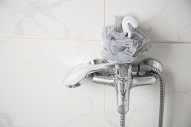 Grey shower puff on faucet in bathroom, space for text