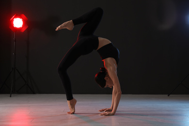 Young professional acrobat exercising in dark studio