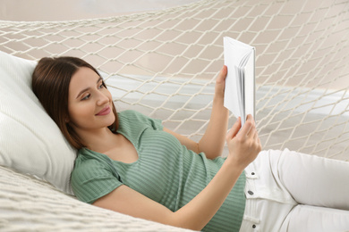 Happy woman with book in hammock at home