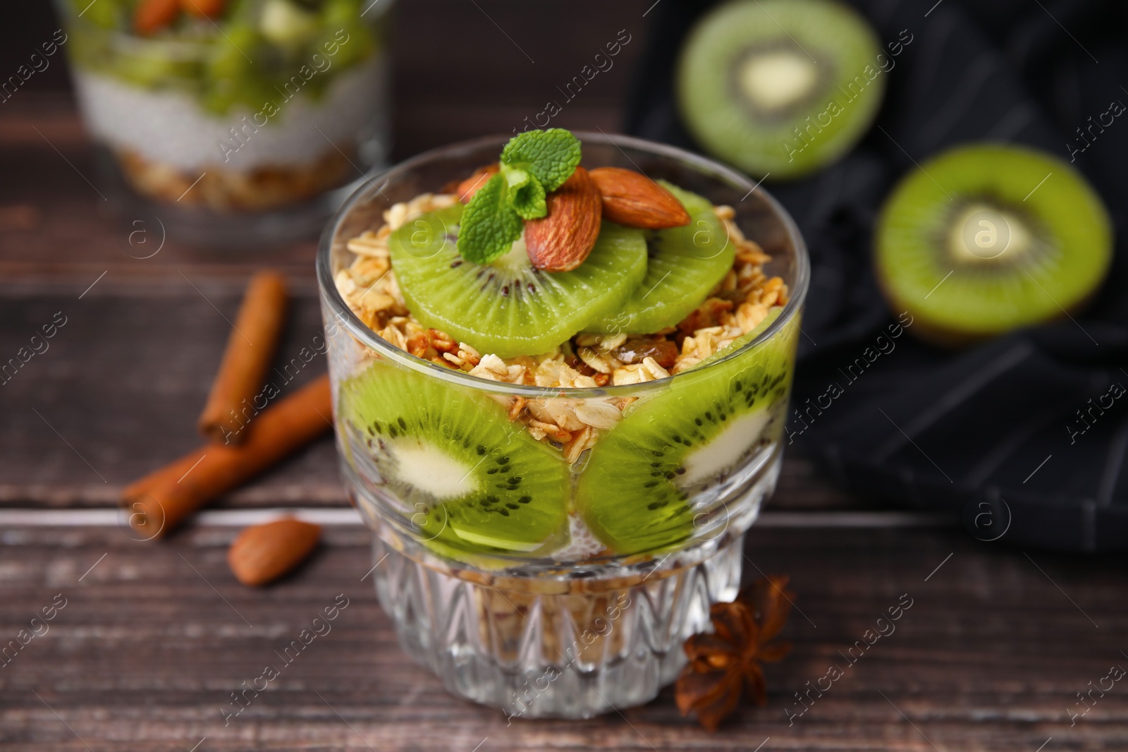 Photo of Delicious dessert with kiwi muesli and almonds on wooden table, closeup