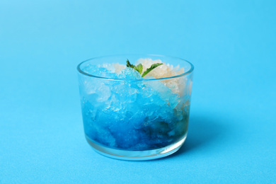 Photo of Shaving ice in glass dessert bowl on light blue background, closeup