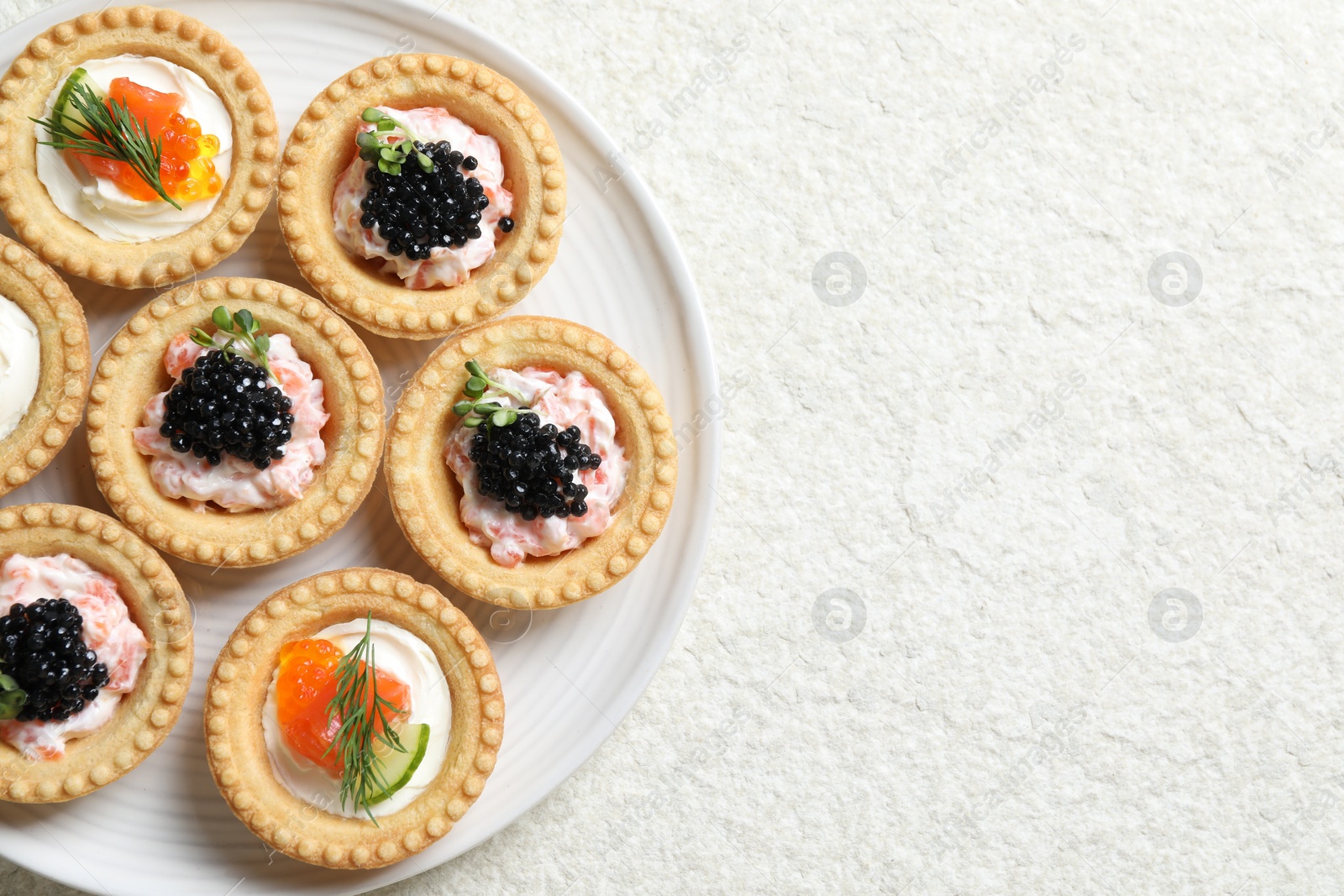 Photo of Delicious canapes with salmon and caviar on beige textured table, top view. Space for text