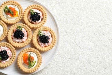 Delicious canapes with salmon and caviar on beige textured table, top view. Space for text