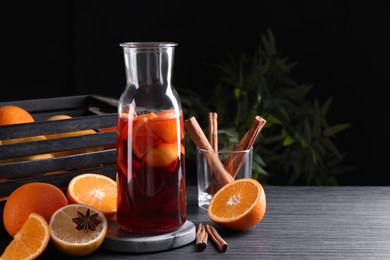 Photo of Aromatic punch drink and ingredients on black table. Space for text