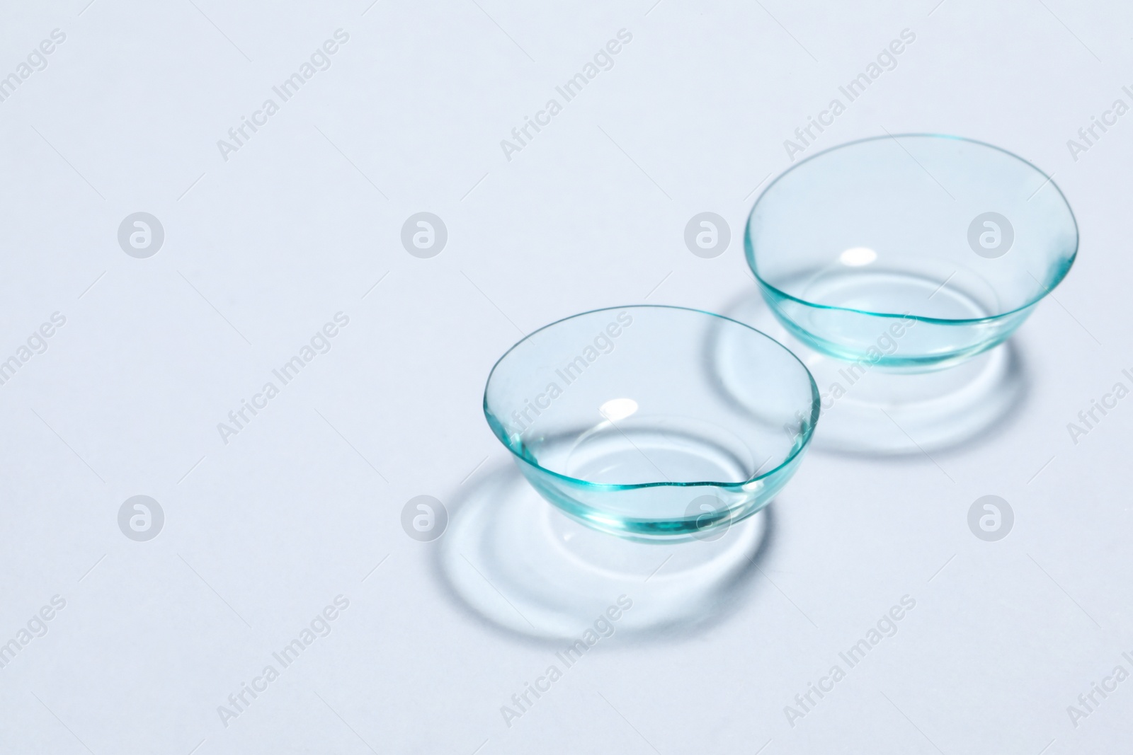 Photo of Pair of contact lenses on white background, space for text