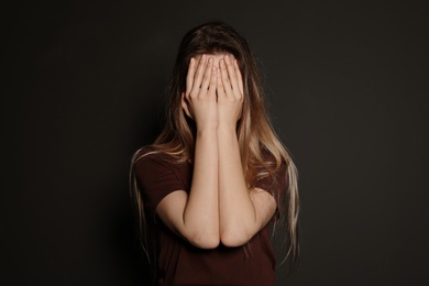 Photo of Upset young woman crying against dark background