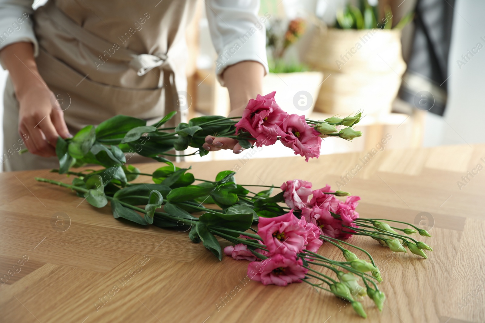 Photo of Florist making beautiful bouquet at table in workshop, closeup