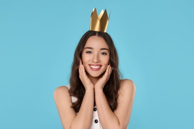 Photo of Beautiful young woman with princess crown on light blue background