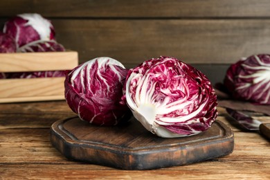 Photo of Whole and cut fresh ripe radicchios on wooden table