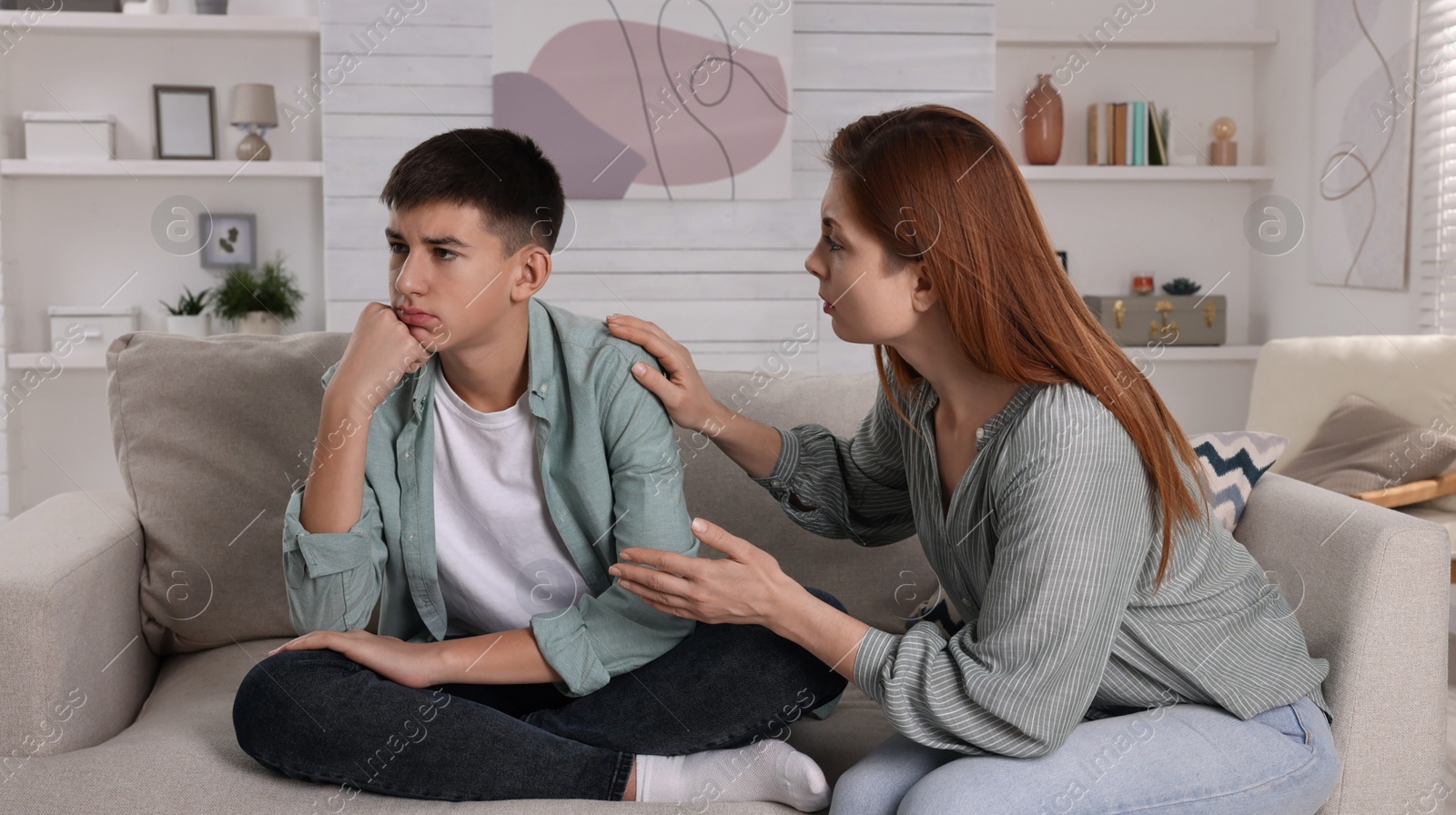 Photo of Mother consoling her depressed son at home. Teenager problems