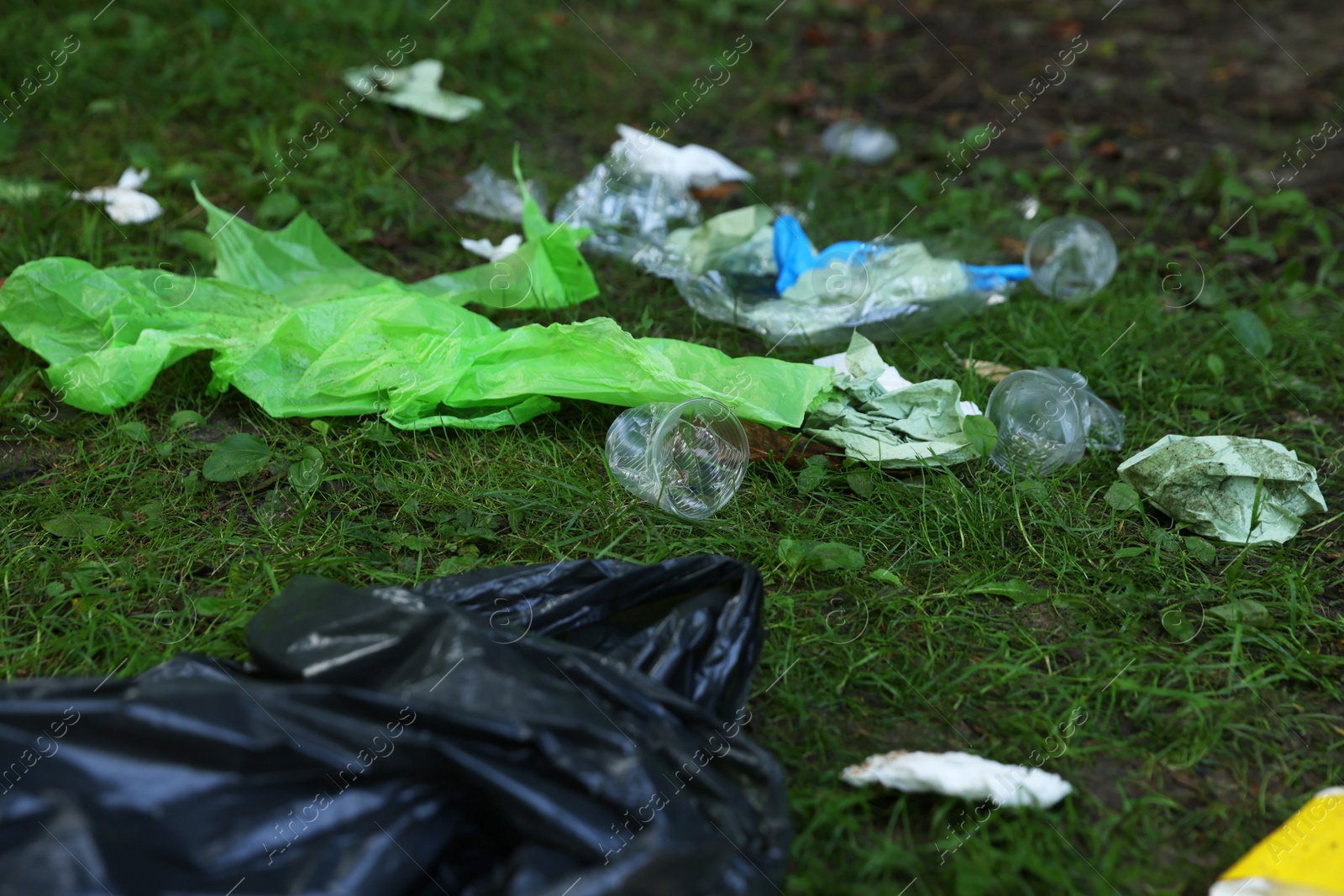 Photo of Different garbage scattered on green grass outdoors