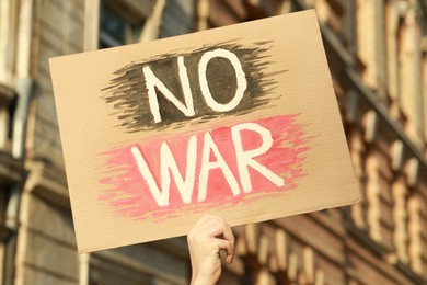 Photo of Woman holding poster with words No War outdoors
