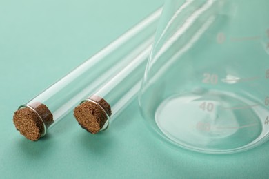 Photo of Flask and test tubes on turquoise background, closeup. Laboratory glassware