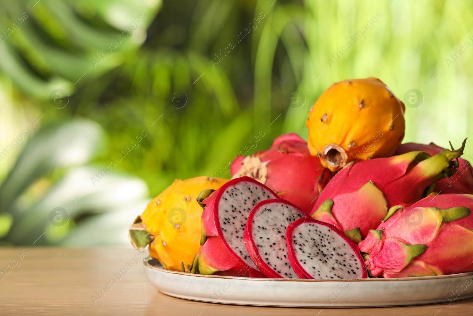 Photo of Tray with delicious cut and whole dragon fruits (pitahaya) on wooden table. Space for text