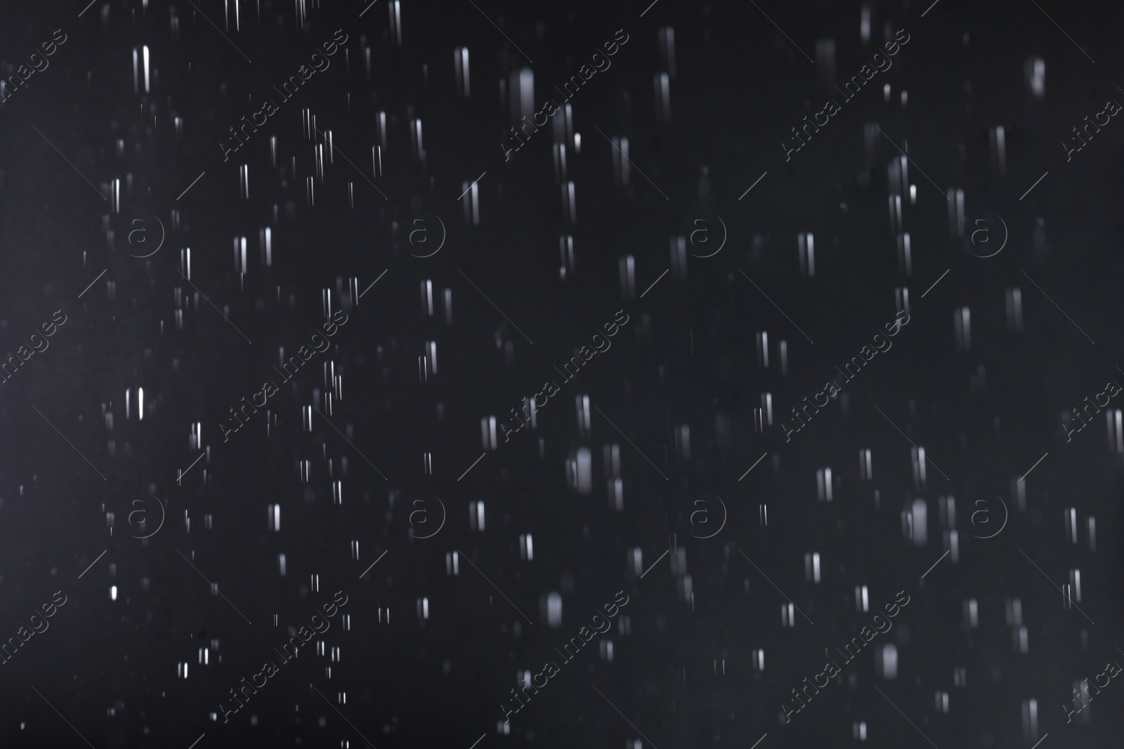 Photo of Rain drops falling down against dark background