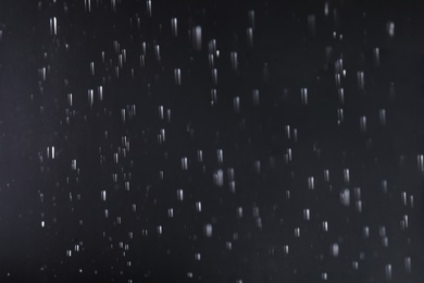 Photo of Rain drops falling down against dark background