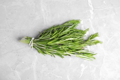 Photo of Bunch of fresh rosemary on grey marble table, top view