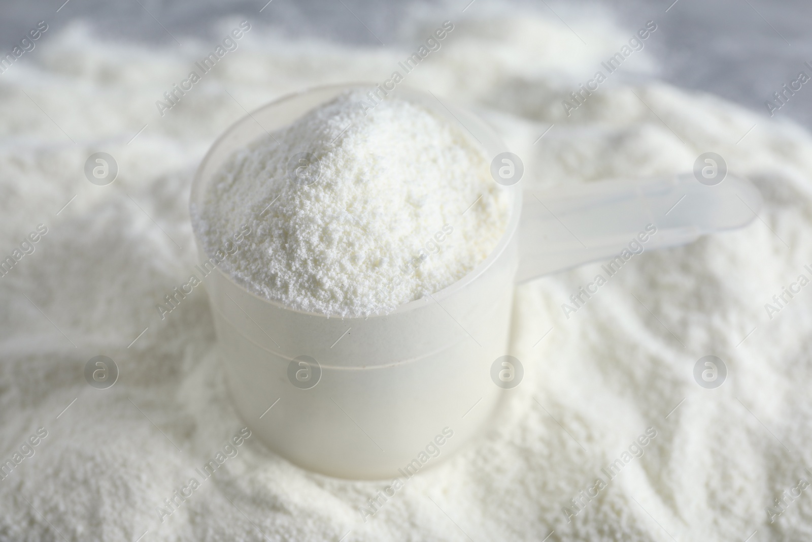 Photo of Scoop and pile of protein powder on table, closeup