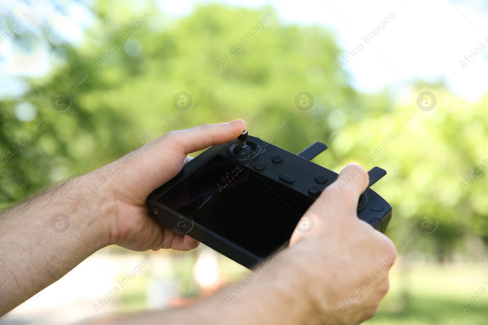 Photo of Man holding new modern drone controller outdoors, closeup of hands