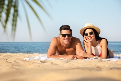 Photo of Happy couple resting on sunny beach. Space for text