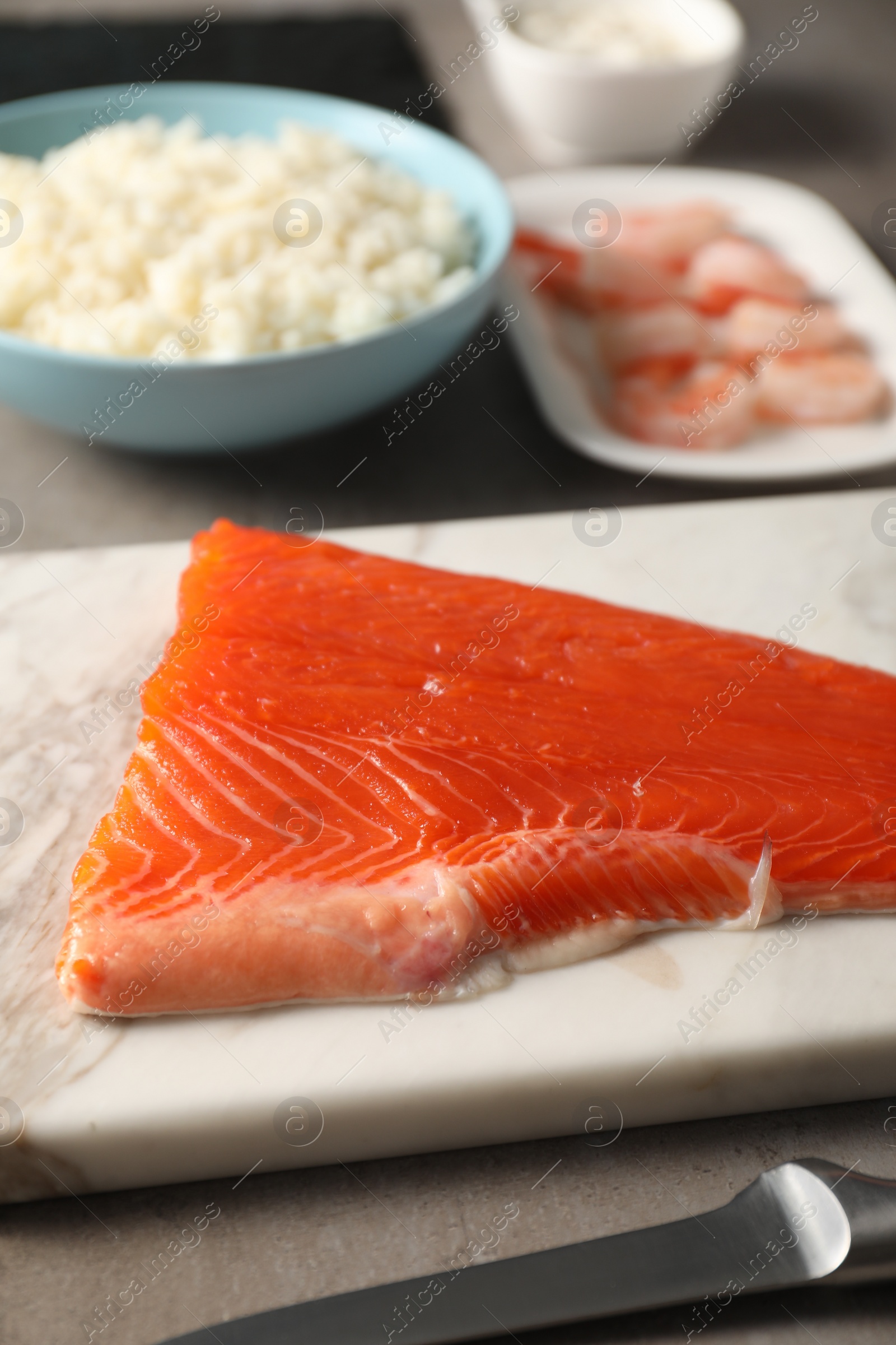 Photo of Fresh salmon and other ingredients for sushi on grey table, closeup