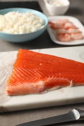 Photo of Fresh salmon and other ingredients for sushi on grey table, closeup