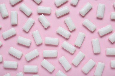 Photo of Tasty white chewing gums on pale pink background, flat lay