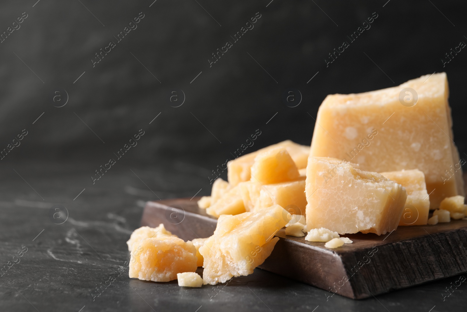 Photo of Pieces of delicious parmesan cheese on black table, closeup. space for text