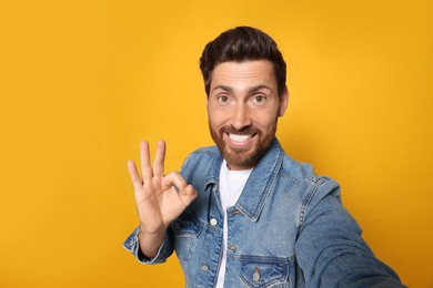 Photo of Funny bearded man taking selfie on orange background