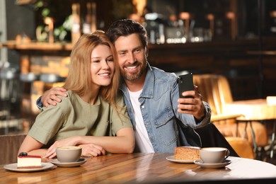 Photo of Romantic date. Happy couple taking selfie in cafe