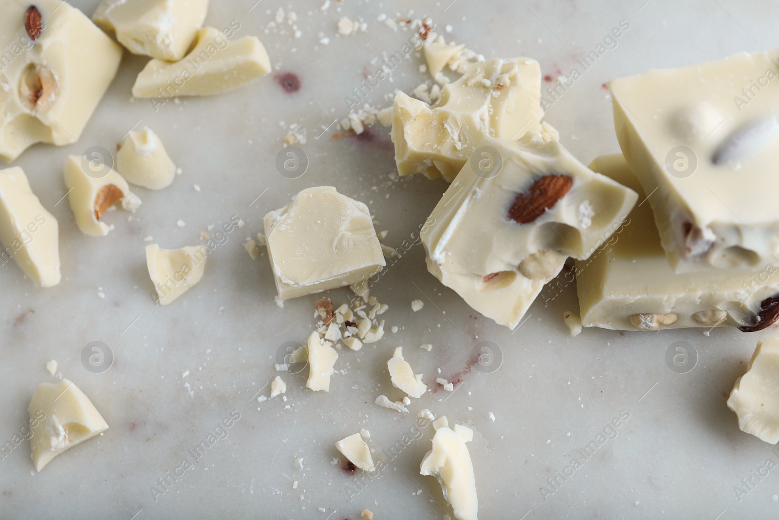 Photo of Pieces of white chocolate with nuts on light table