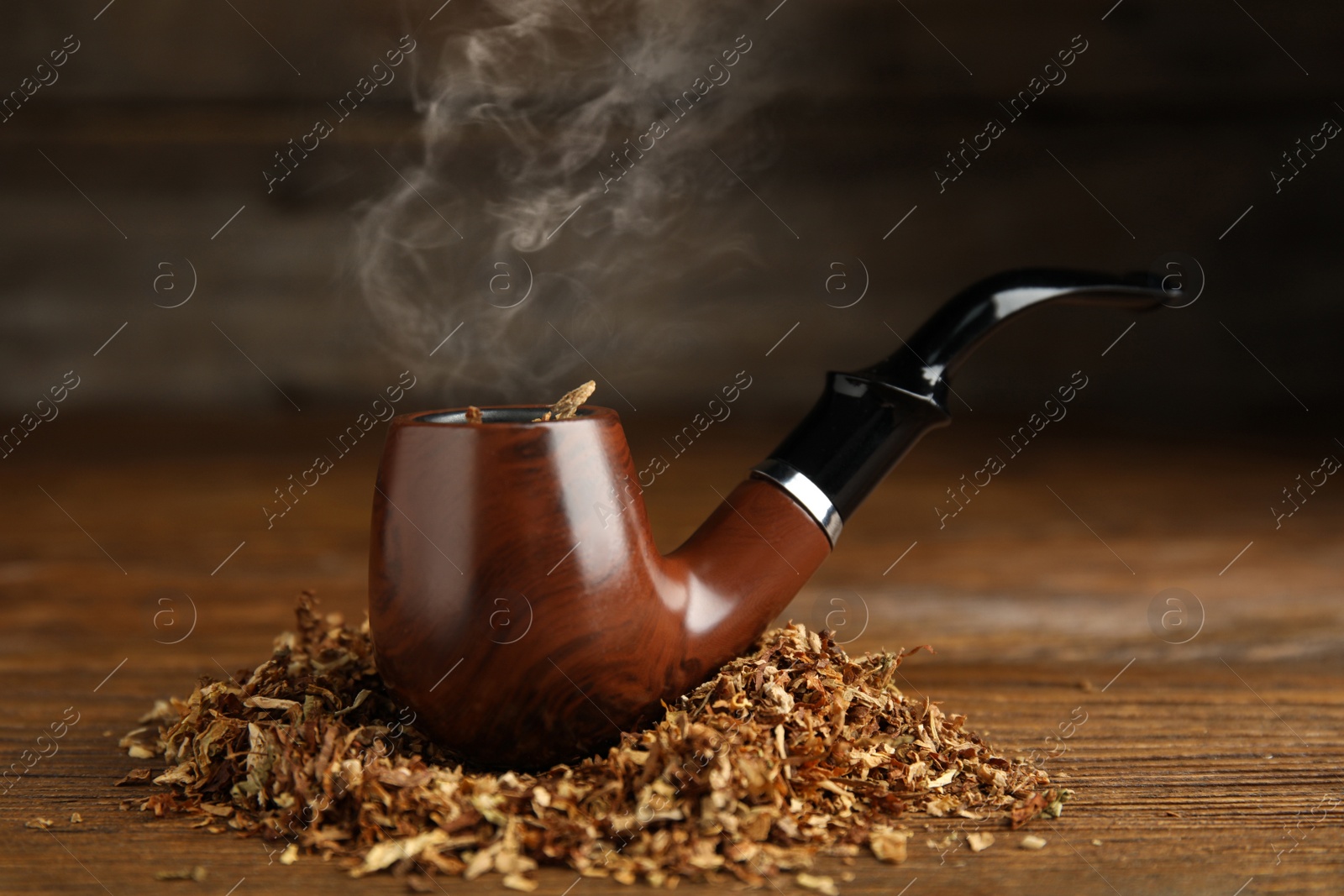 Photo of Classic smoking pipe with tobacco on wooden table