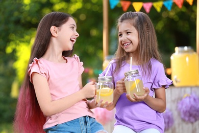 Cute little girls with natural lemonade in park. Summer refreshing drink