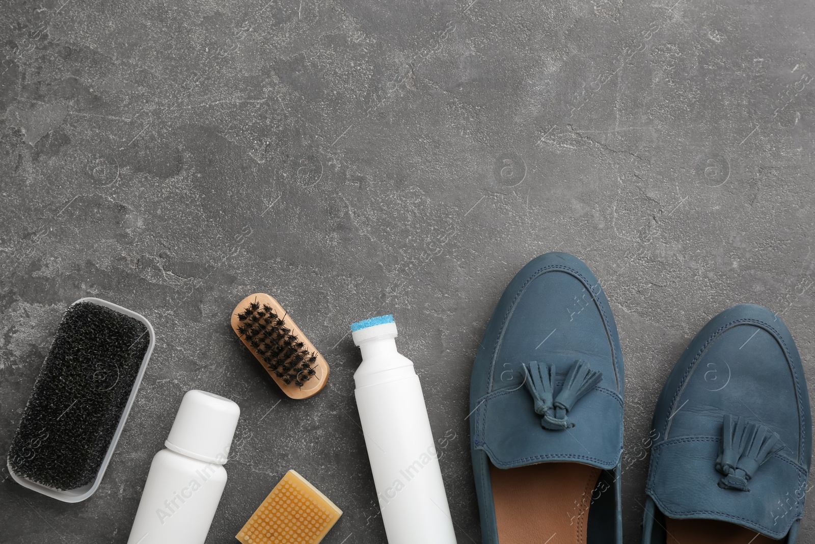 Photo of Stylish footwear with shoe care accessories on grey stone table, flat lay. Space for text