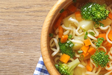 Photo of Bowl of fresh homemade vegetable soup on wooden background, top view. Space for text