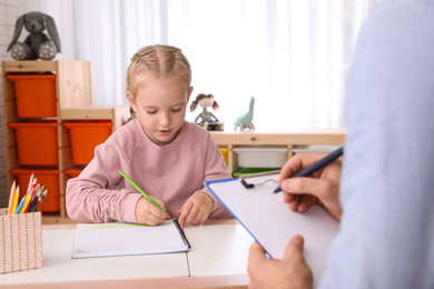 Little girl on appointment with child psychotherapist indoors